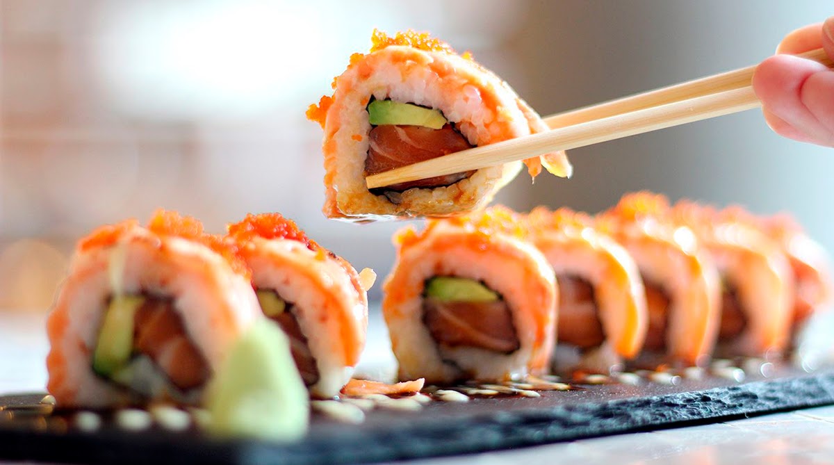 cropped-image-of-person-holding-sushi-at-table-royalty-free-image-691103589-1536344826.jpg